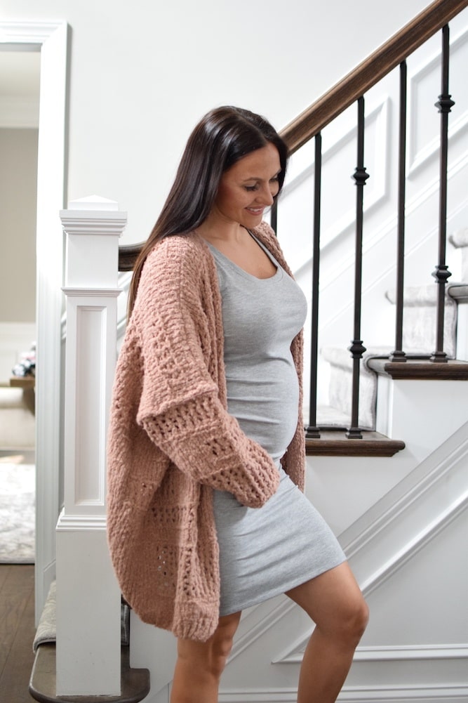 pregnant woman wearing a grey ruched dress and a pink cardigan