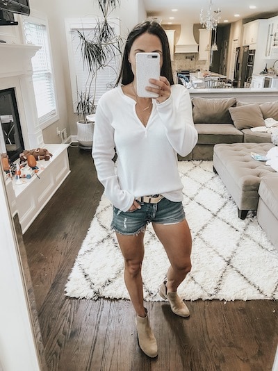 woman wearing a waffle knit v neck top, denim shorts, and tan booties