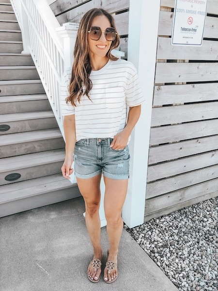 woman wearing a striped tshirt, denim shorts, and flip flops