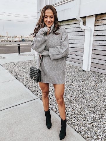 A woman in a grey sweater dress and black booties.