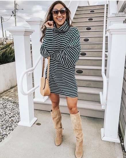 woman wearing an oversized striped dress and tan knee high boots.