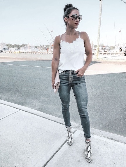 a woman wearing a white tank top, skinny jeans, and snakeskin booties