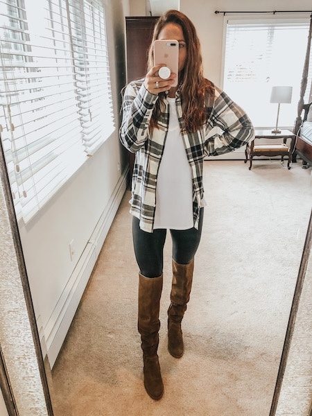a woman wearing a plaid button up with leggings and knee high boots