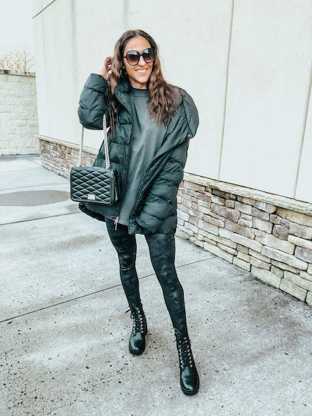 A woman wearing a black jacket, black leggings, and black combat boots.