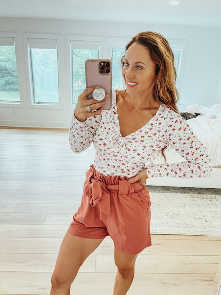woman wearing a floral top and high waisted shorts
