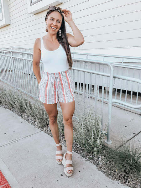 woman wearing striped shorts and a white tank top