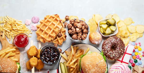 A bunch of junk food like french fries, cheeseburgers, waffles, donuts, and more.