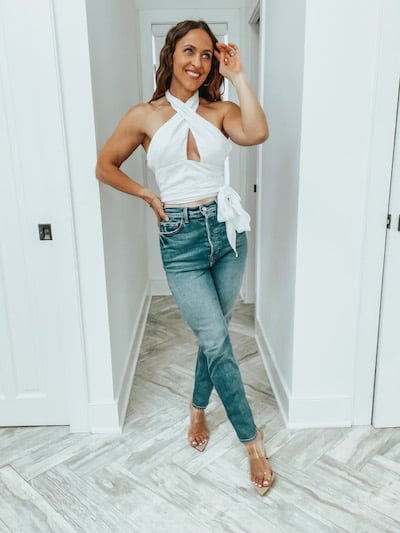 woman posing in a white halter top and jeans