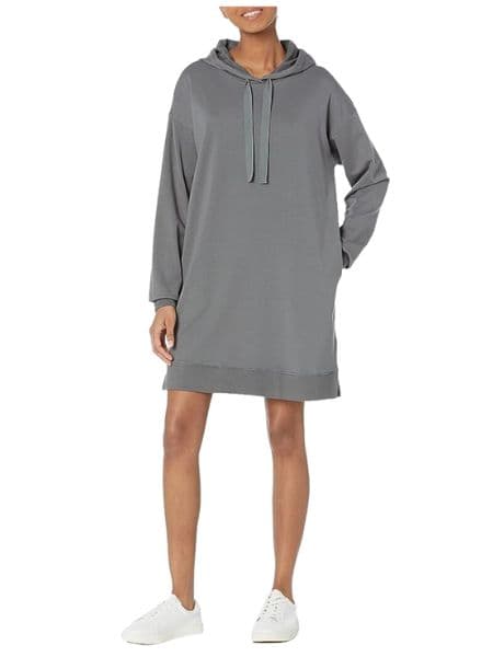 A woman wearing a grey sweatshirt dress and white sneakers.