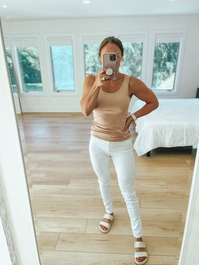 woman wearing white jeggings with a tan tank top and white sandals
