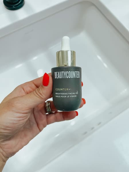 A woman holding a bottle of Beautycounter face oil.