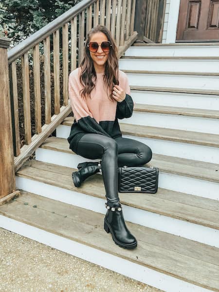 A woman sitting on steps wearing a colorblock sweater, leggings, and chunky chelsea boots
