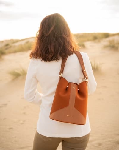 woman holding a tan suede purse