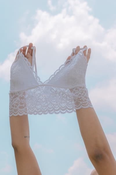 woman holding up a white lace bralette