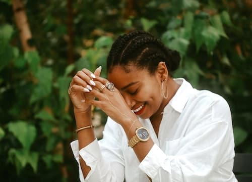 a woman wearing a white shirt with a gold watch on one hand and a gold bracelet on the other