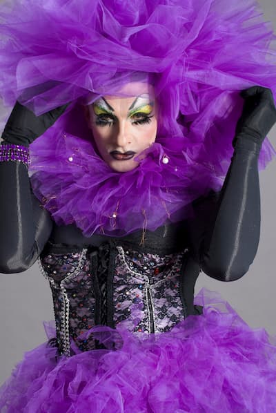 A man dressed up in a purple outfit for a drag show