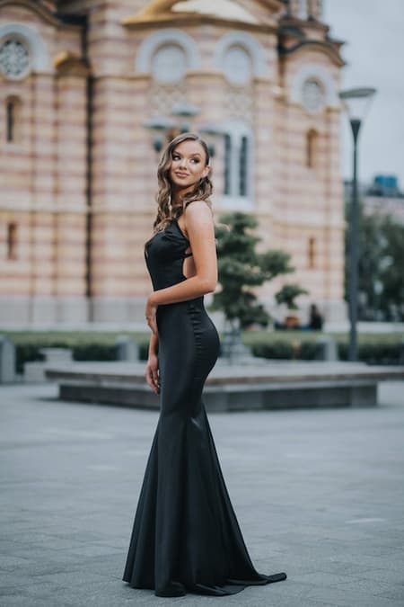 A woman wearing a long black evening gown for a night at the symphony.