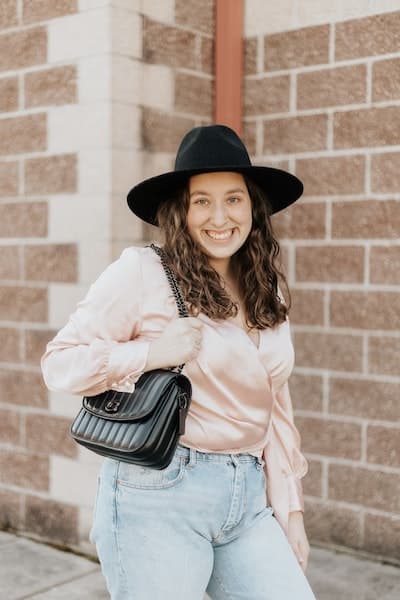 woman wearing a shirt from a store like old navy, jeans, a black hat, and a black purse