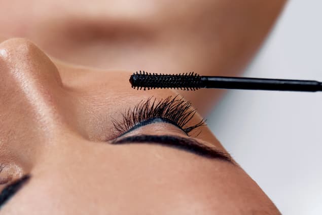 A woman having her eyelash extensions brushed.