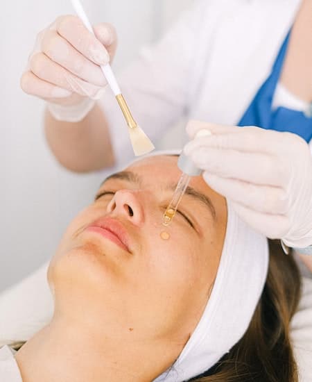 A woman having a chemical peel facial done on her face.