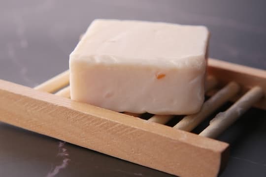 A white bar of sea moss soap on a wood soap dish.