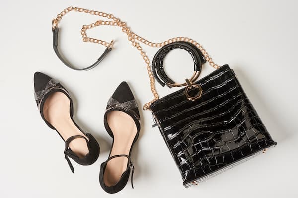 A flat lay of women's black high heels and a black purse.