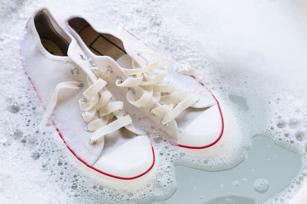A pair of white sneakers soaking in a tub.