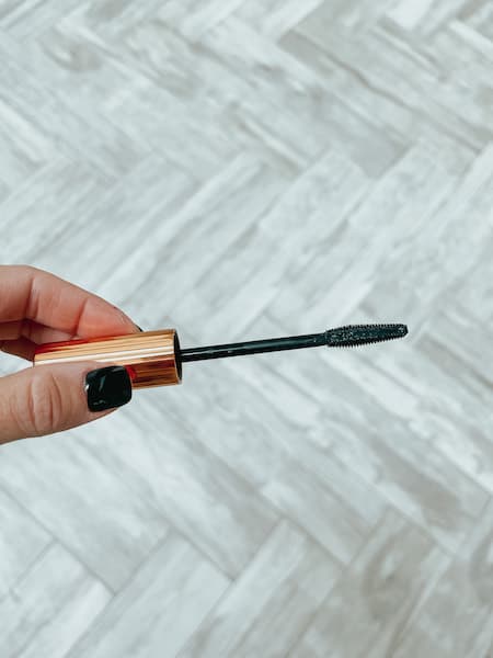 A woman holding the applicator to the Charlotte Tilbury Push Up Lashes mascara.