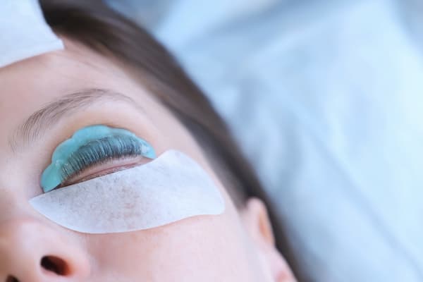 A woman at a lash lift appointment with her eyes closed getting ready for solution to be applied.
