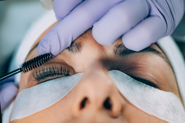 A woman having her eyelashes brushed at the end of her lash lift appointment.