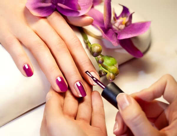A woman having purple nail lacquer applied to her nails.