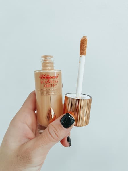 A woman holding the bottle and applicator to the charlotte tilbury hollywood flawless filter.