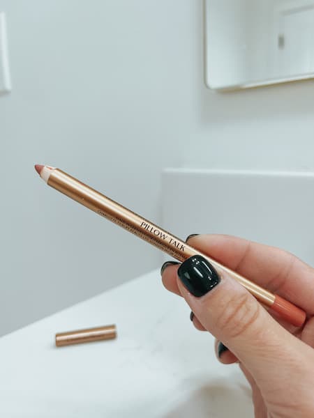 A woman holding the pillow tip lip cheat from Charlotte Tilbury.
