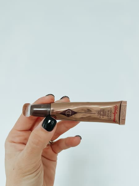 A woman holding the Charlotte Tilbury Contour Wand in the light/medium color. 