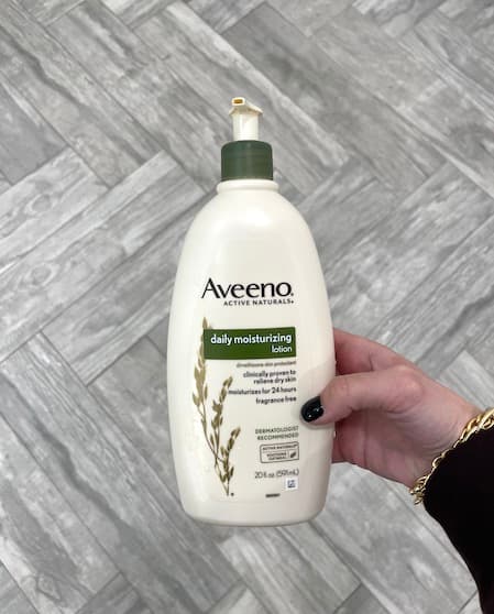 A woman holding a bottle of veeno daily moisturizing lotion.