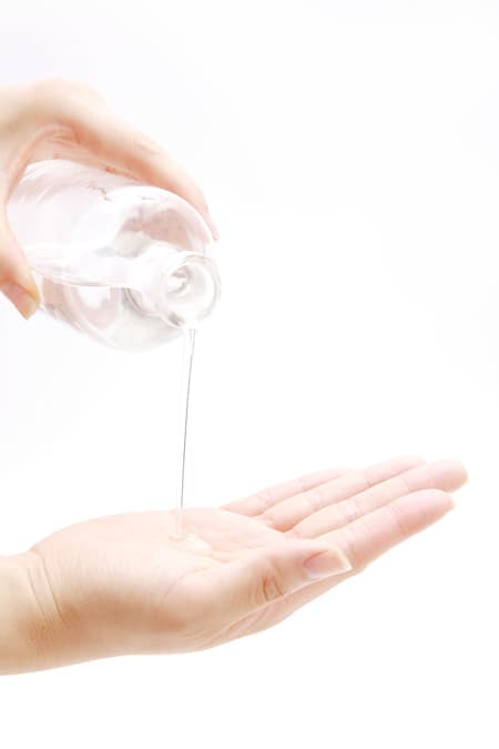 A woman pouring micellar water into the palm of her hand.