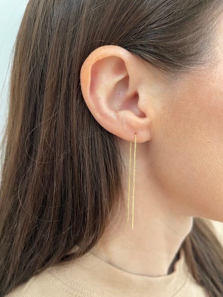 A woman wearing threader earrings.