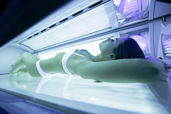 A woman in a white bikini laying in a tanning bed.