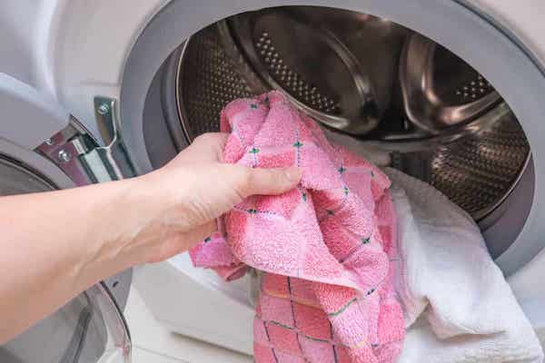 A woman putting small towels in a dryer.