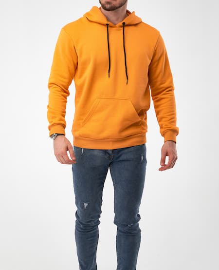 A man wearing an orange hoodie sweatshirt and jeans.