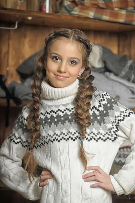 A smiling girl wearing a patterned turtleneck sweater.