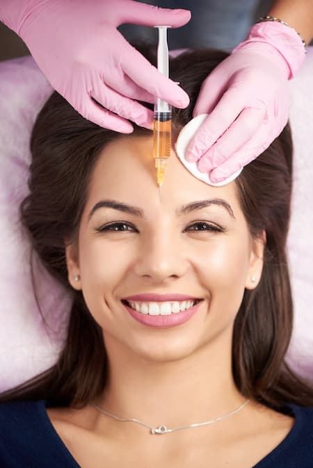 A woman having dermal filler injected into her forehead.