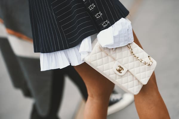 A woman holding a white Chanel bag.