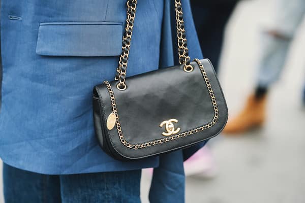 A woman wearing a black Chanel purse.