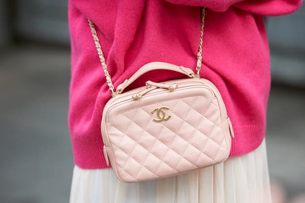 A woman wearing a light pink Chanel purse.