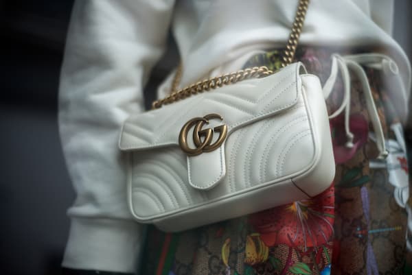 A woman wearing a white Gucci crossbody bag.