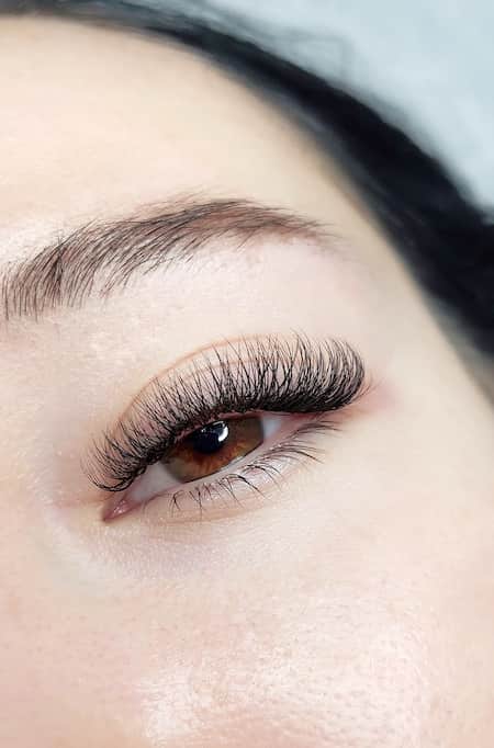 An up-close photo of a woman with lash extensions and brown eyes.