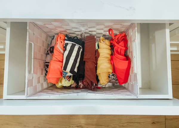 A drawer with a bin of women's swimsuits organized by occassion. 