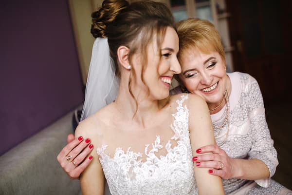 A bride and her mother smiling and laughing together.