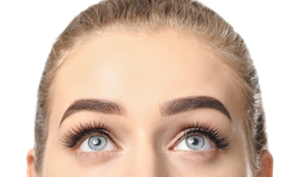 A close up shot of a woman with blue eyes and microbladed eyebrows.